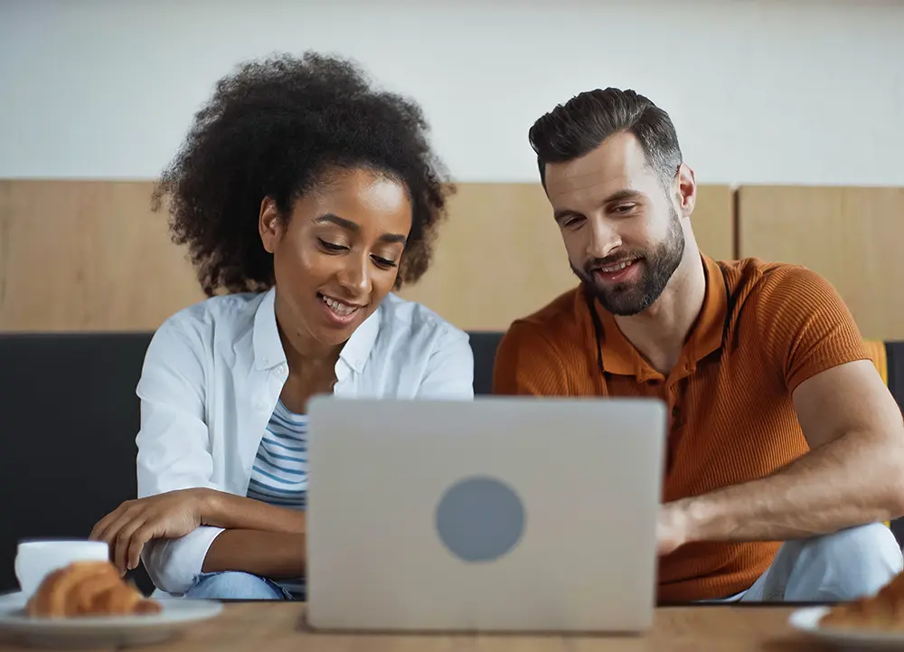 Two people reviewing the online program on a laptop